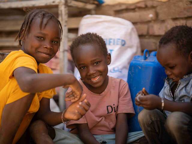 Altuma’s children play inside their shelter after being displaced from Khartoum by war, with their family enduring multiple relocations.