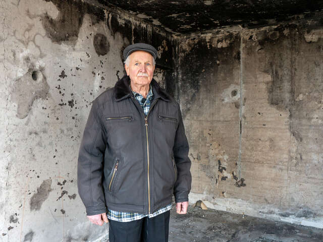 Hyrhorii stands in one of his neighbor's apartments that was destroyed by shelling.