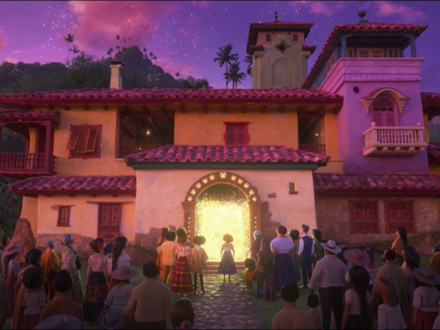 La castia mágica, en morados y rosas, con un resplandor proveniente de la puerta principal. Mirabel está de pie frente a la puerta y toda su familia y todo el pueblo están detrás de ella.