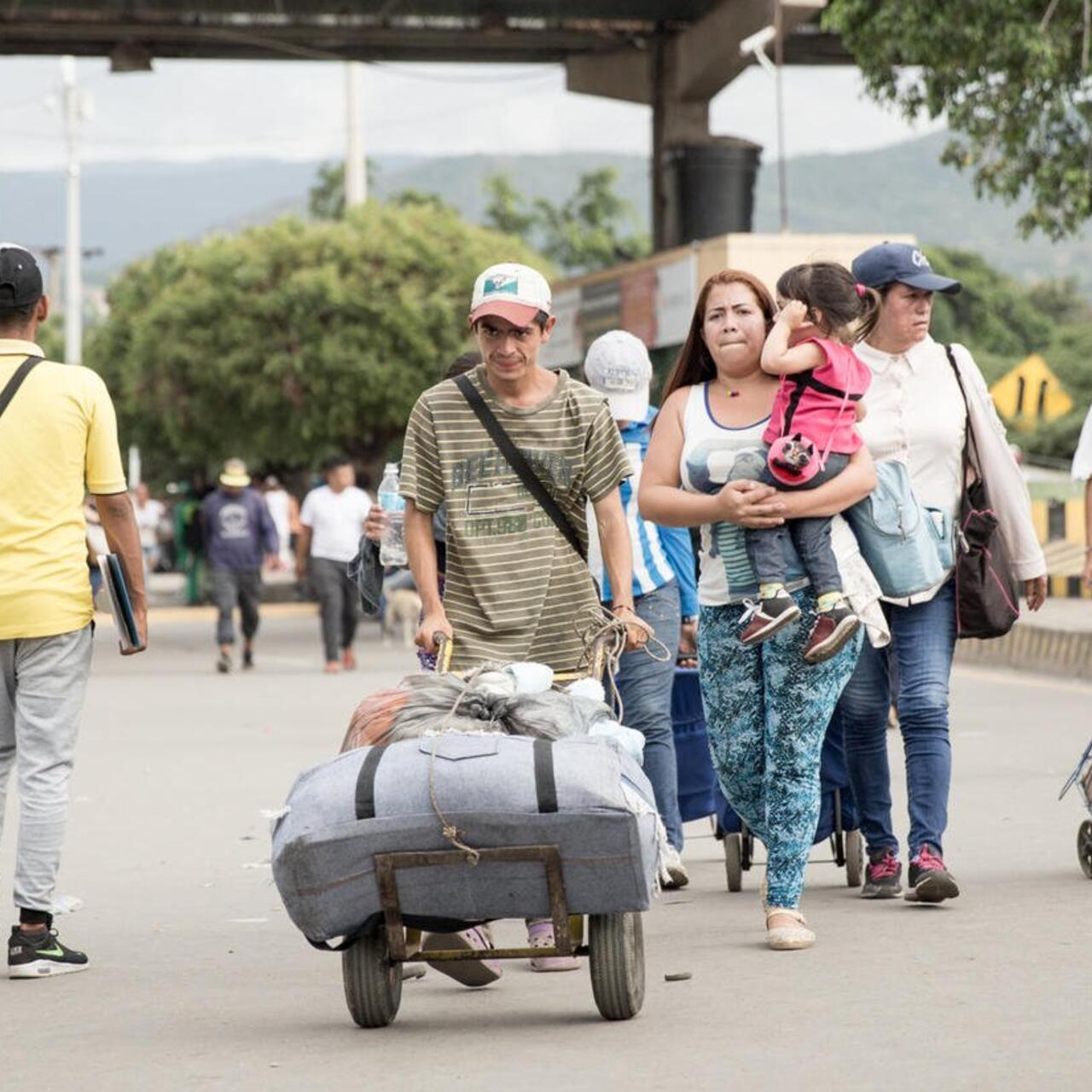 people crossing a border and carrying stuff