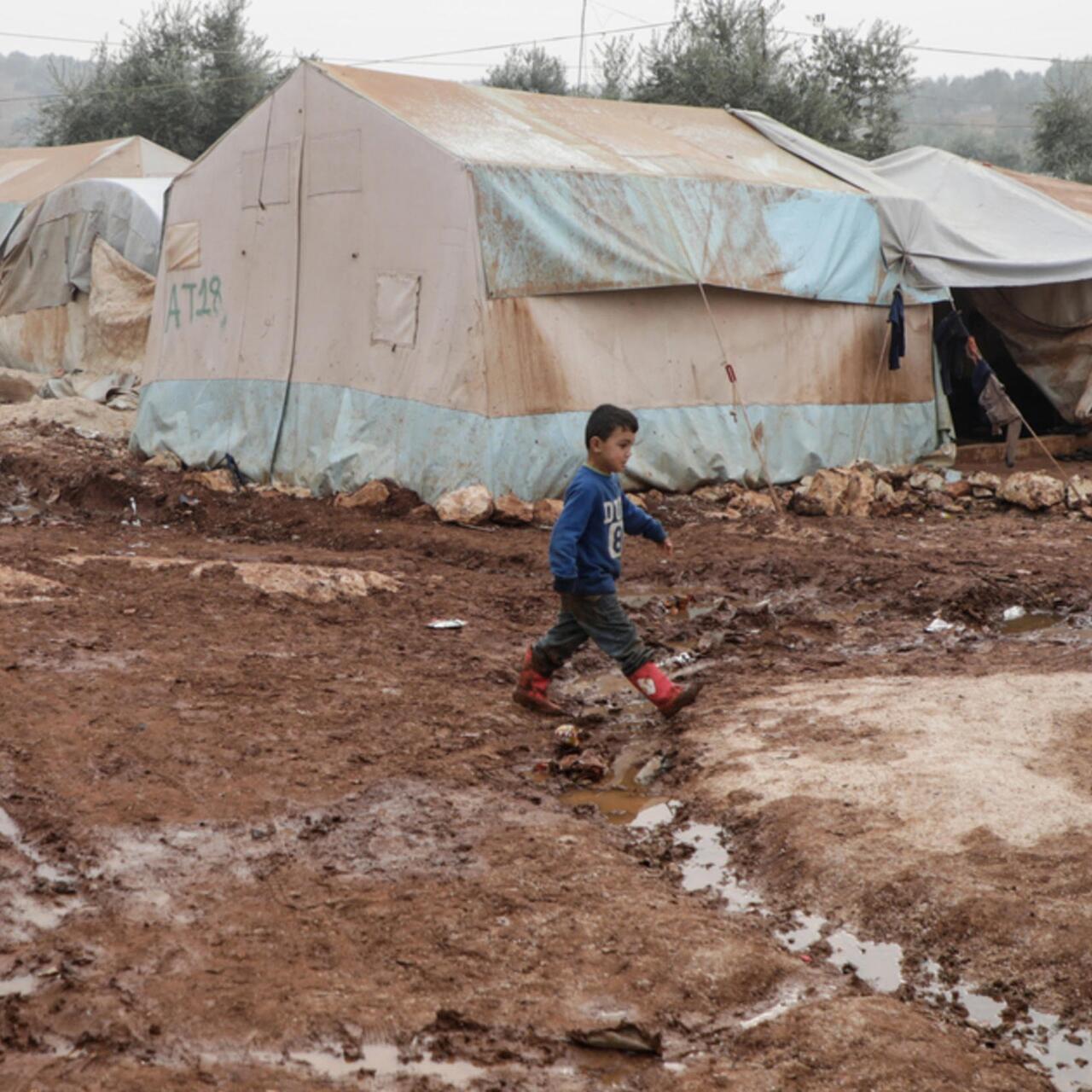 A boy walking through muddy barracks 