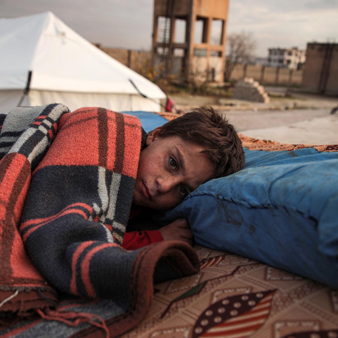 A Syrian child sleeps in the open at a displacement camp near Turkey’s border after fleeing from southern Idlib. 