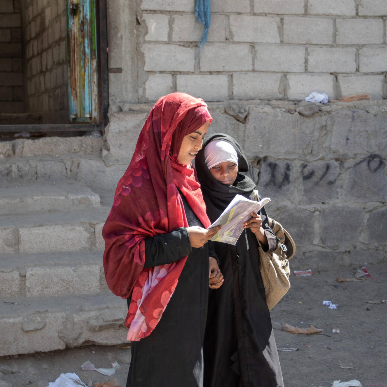 Aisha and Na'aem standing together, reading a book