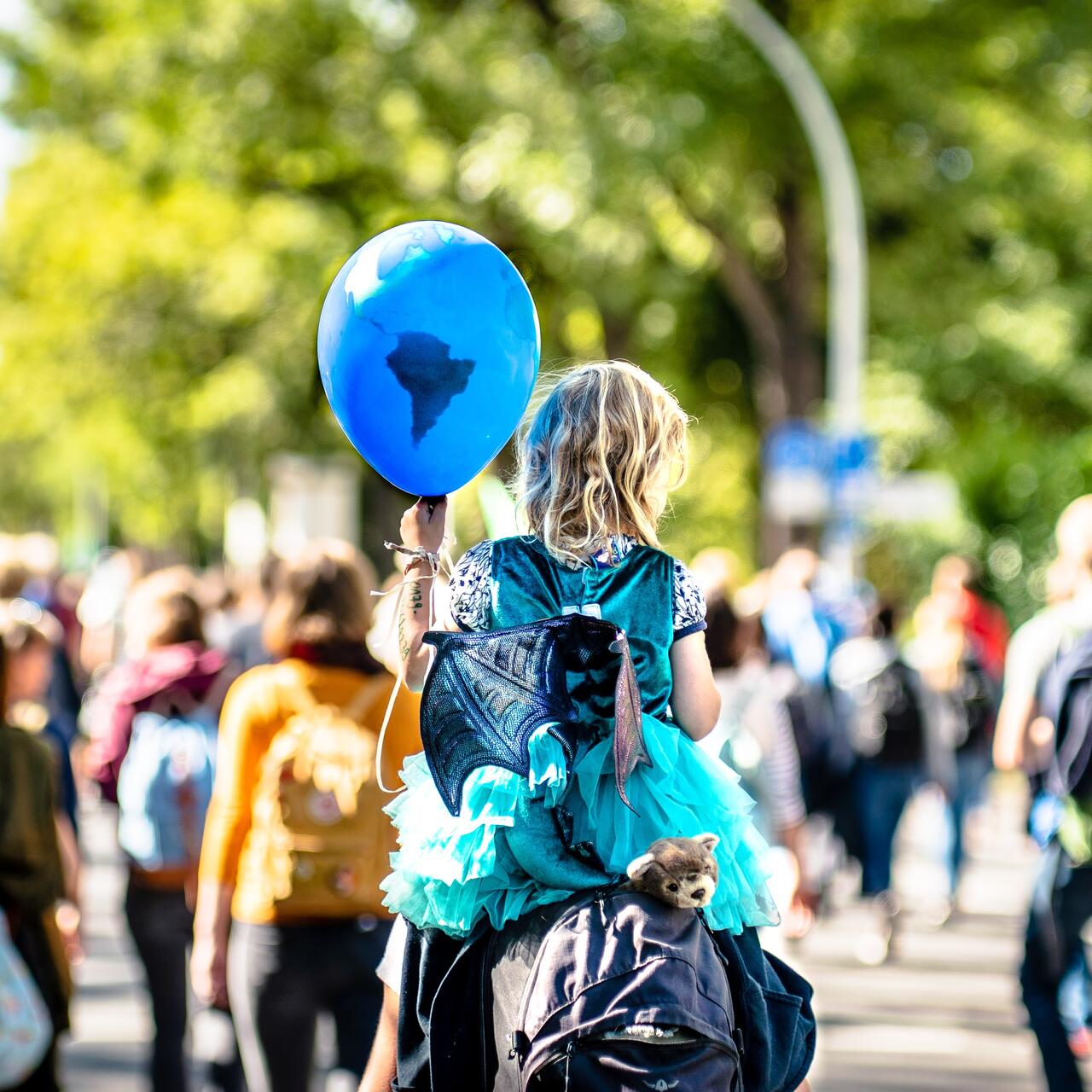 Inmitten eines Protests hält ein Kind einen Luftballon mit einer Weltkarte hoch.