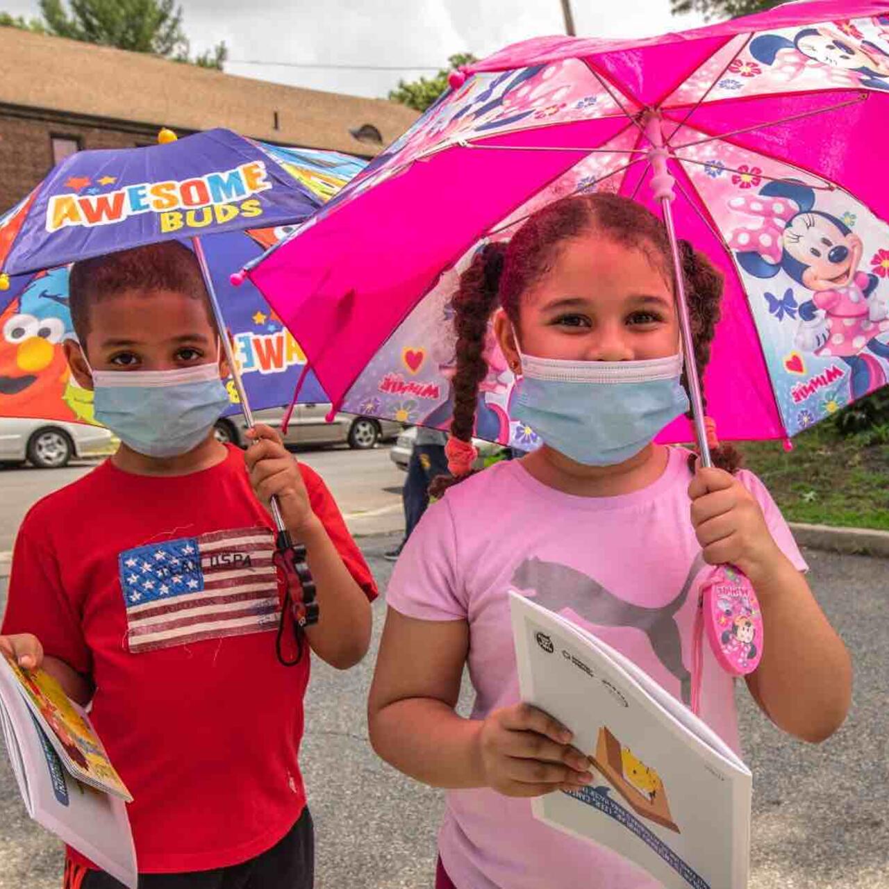 Children in masks with colourful umbrellas during COVID-19