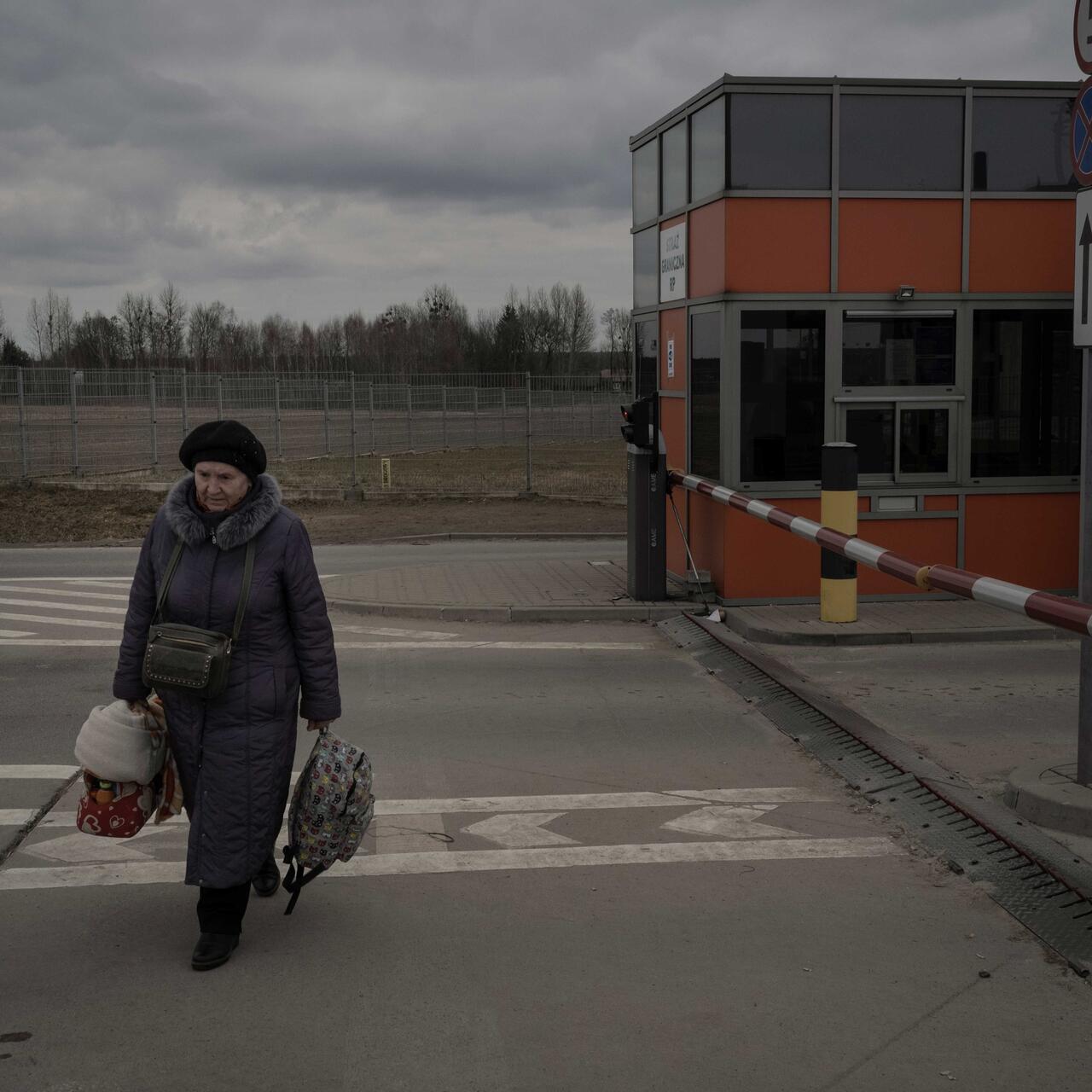 Frau mit Taschen läuft an einem Grenzübergang an der polnisch-ukrainischen Grenze entlang