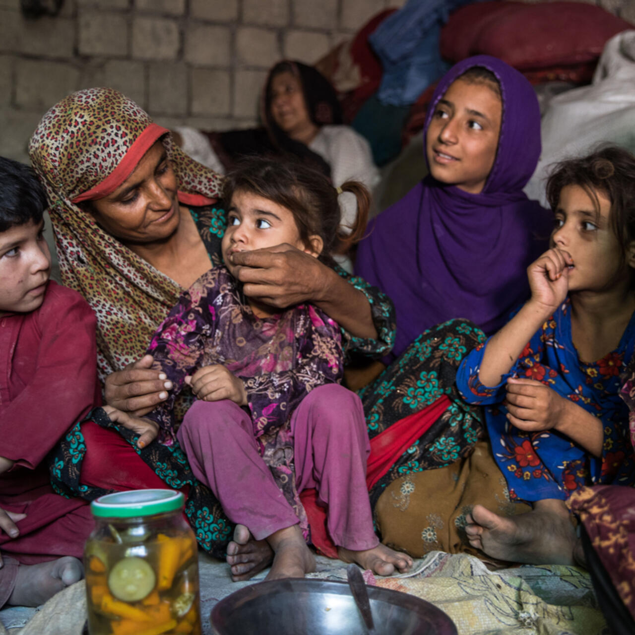 Sajida, her husband Rahmanullah Zarjan with their children on the floor of their home.