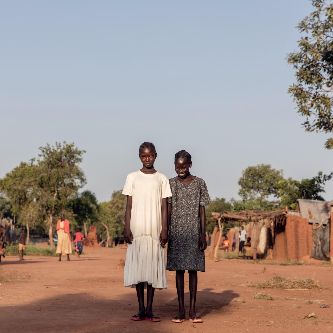 Two girls pose for a picture in South Sudan. They are both smiling.