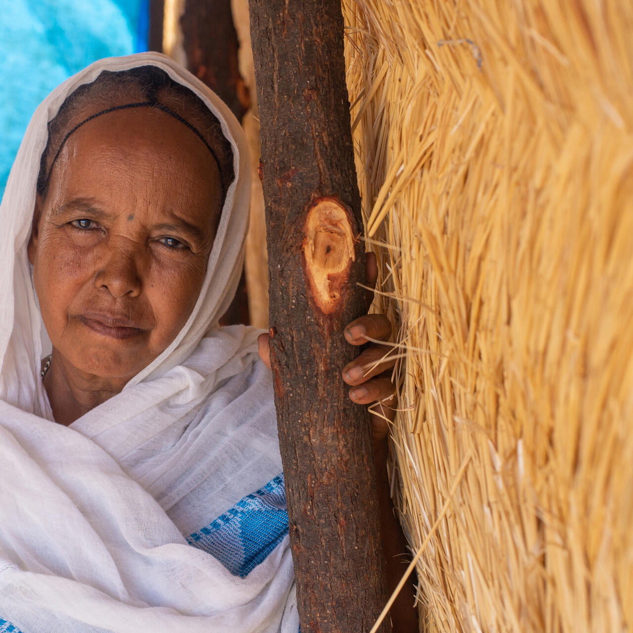 A woman poses for a picture near a makeshift structure in Sudan.