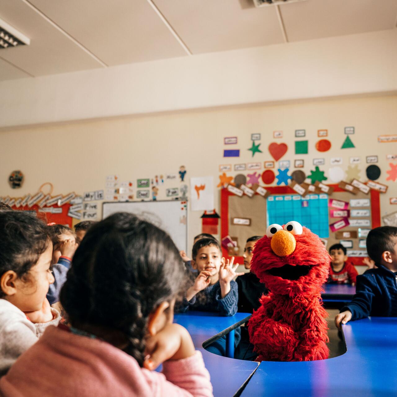 Children in a school classroom with character from Sesame Street