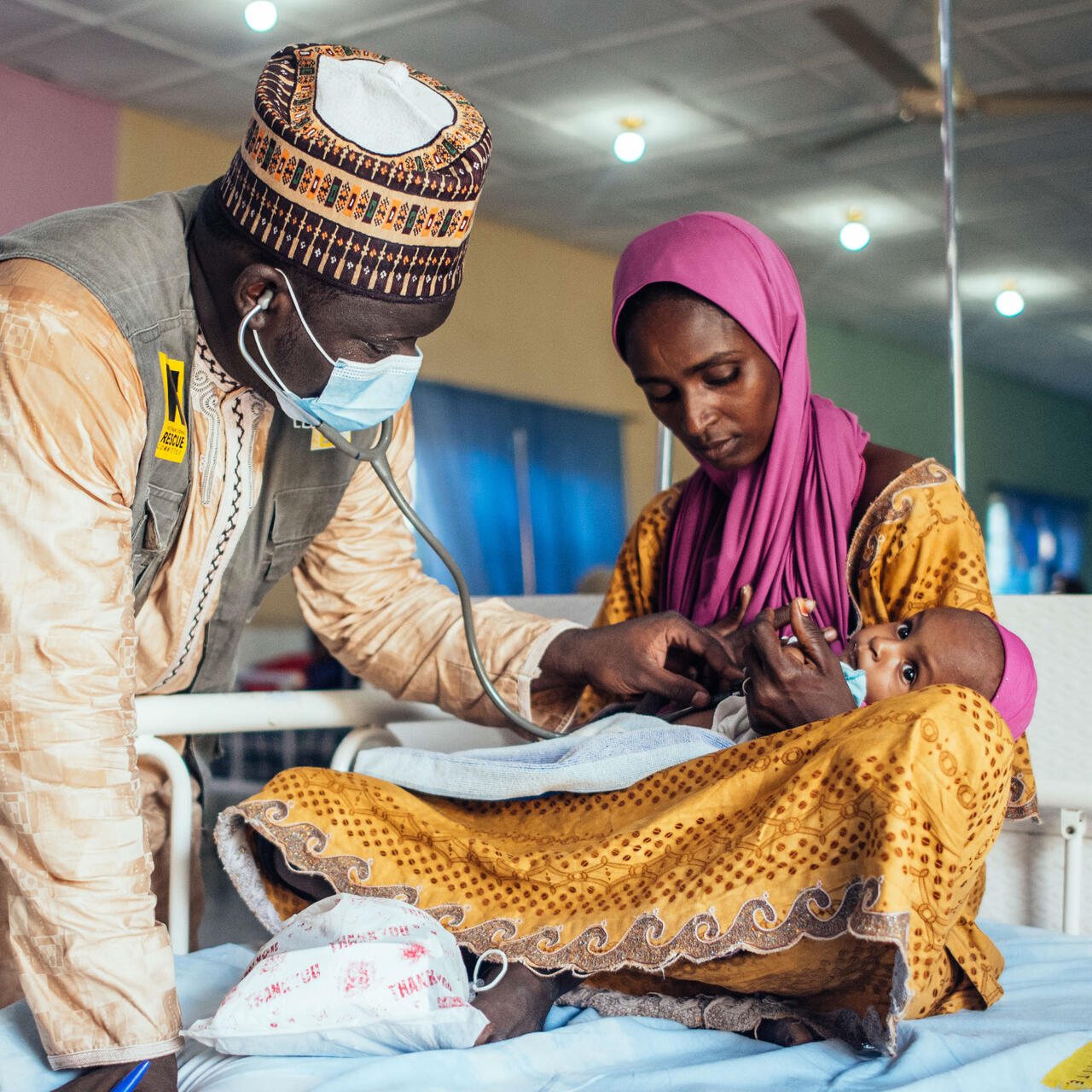 An IRC health officer screens a child at a health facility.