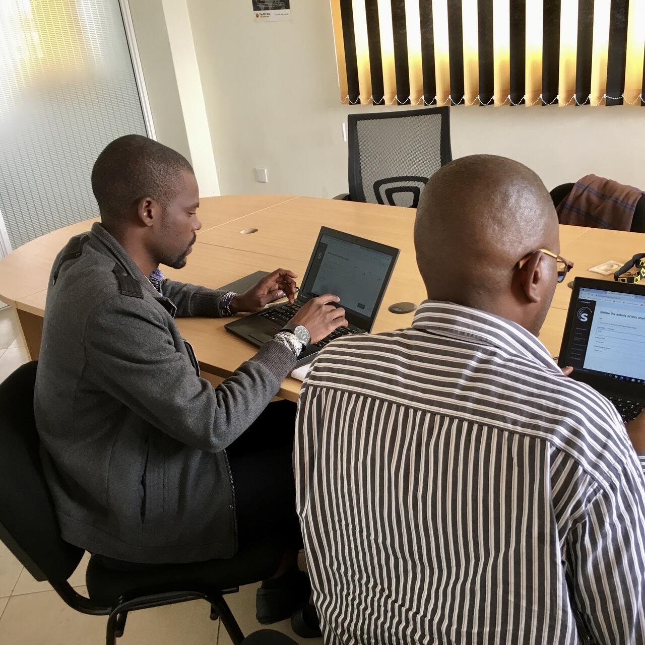 Two people working on laptops seated at a desk.