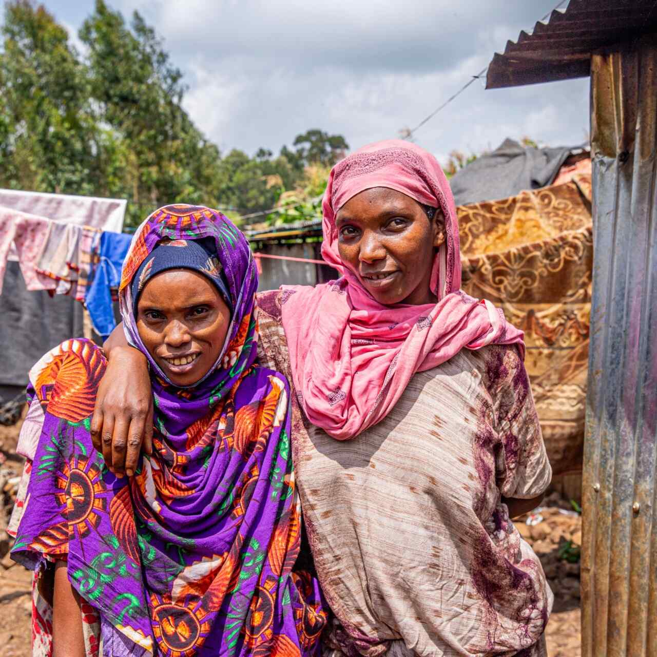 Two neighbors pose for a photo outside their home at the Keyra IDP site, Ethiopia.