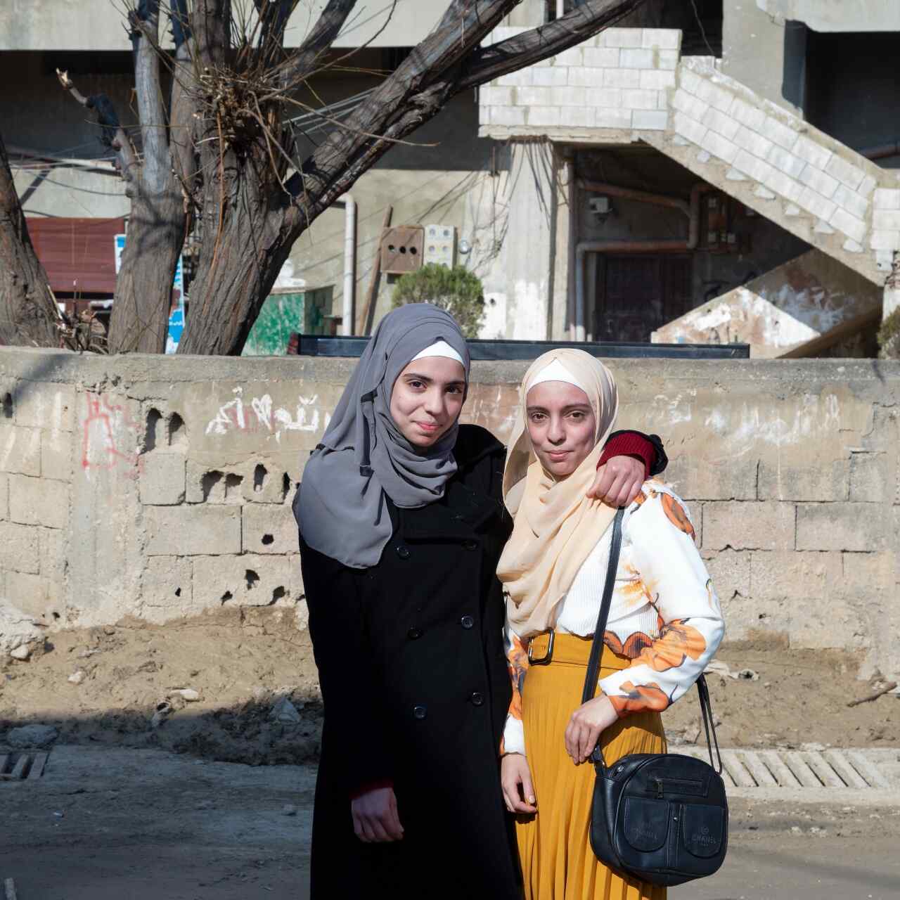 Two girls stand together and pose for a photo outside