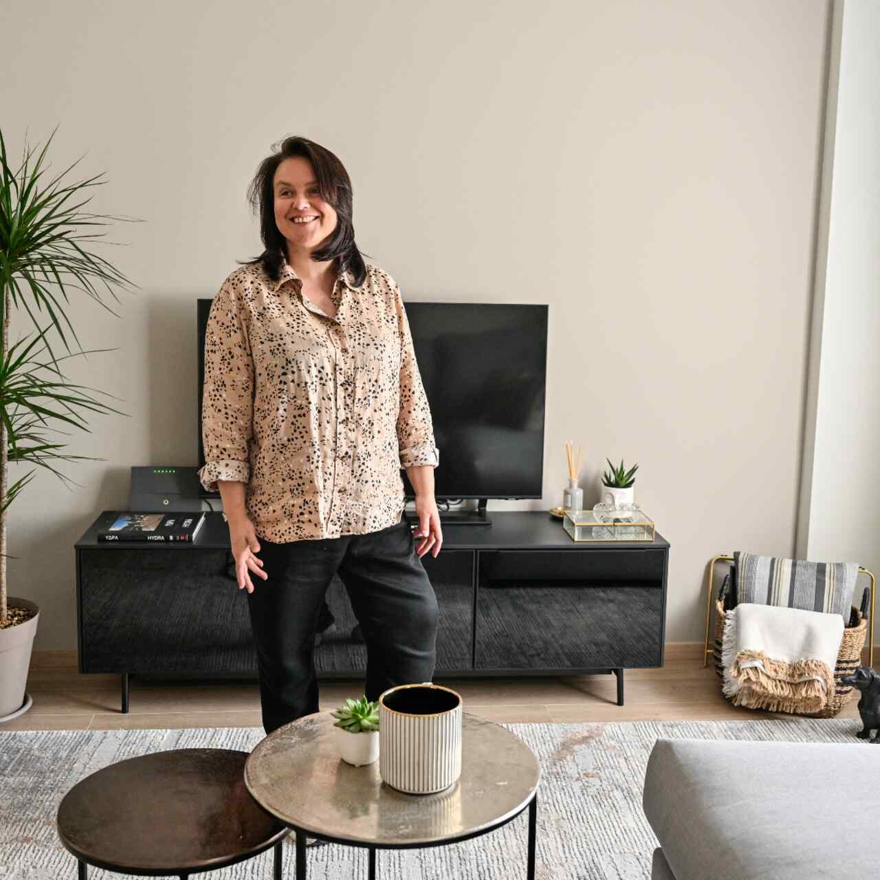 Alisa stands in the room of a home she has just decorated.