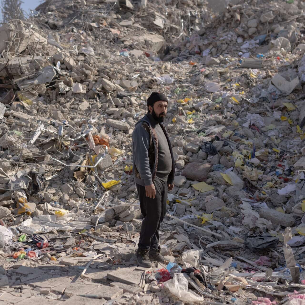 A man stands in the midst of the rubble of a building destroyed in the Syria-Turkey earthquake.