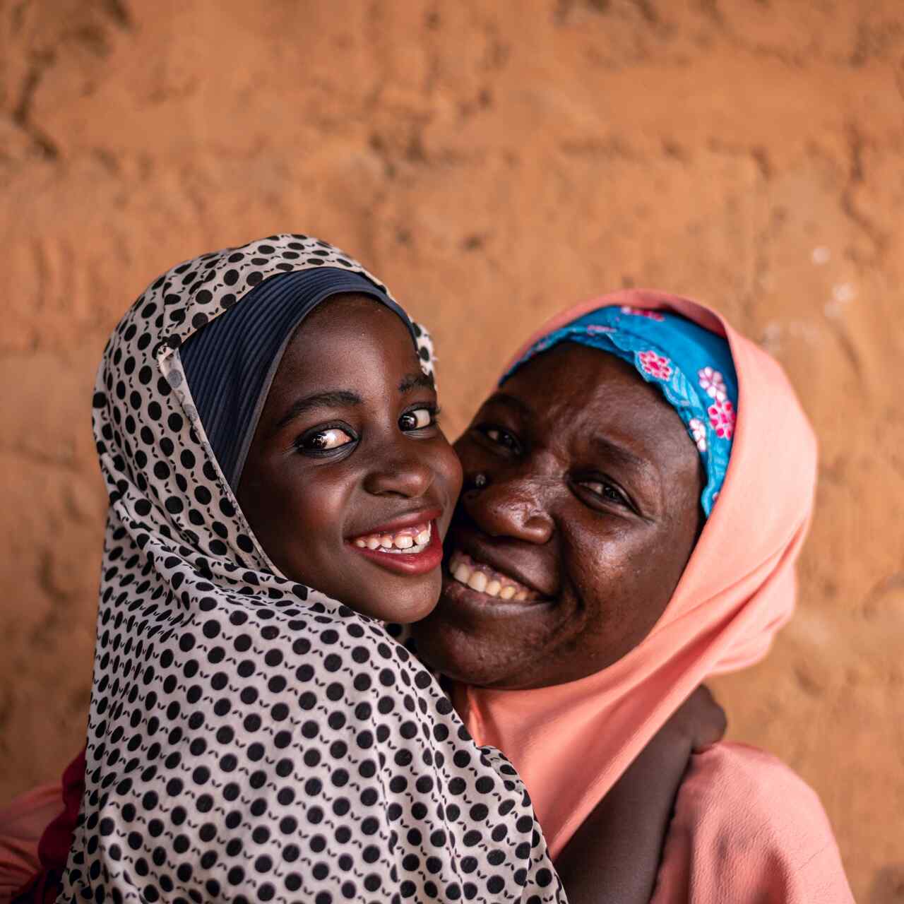 A mother and a daughter embrace and share a smile while posing for a photo.