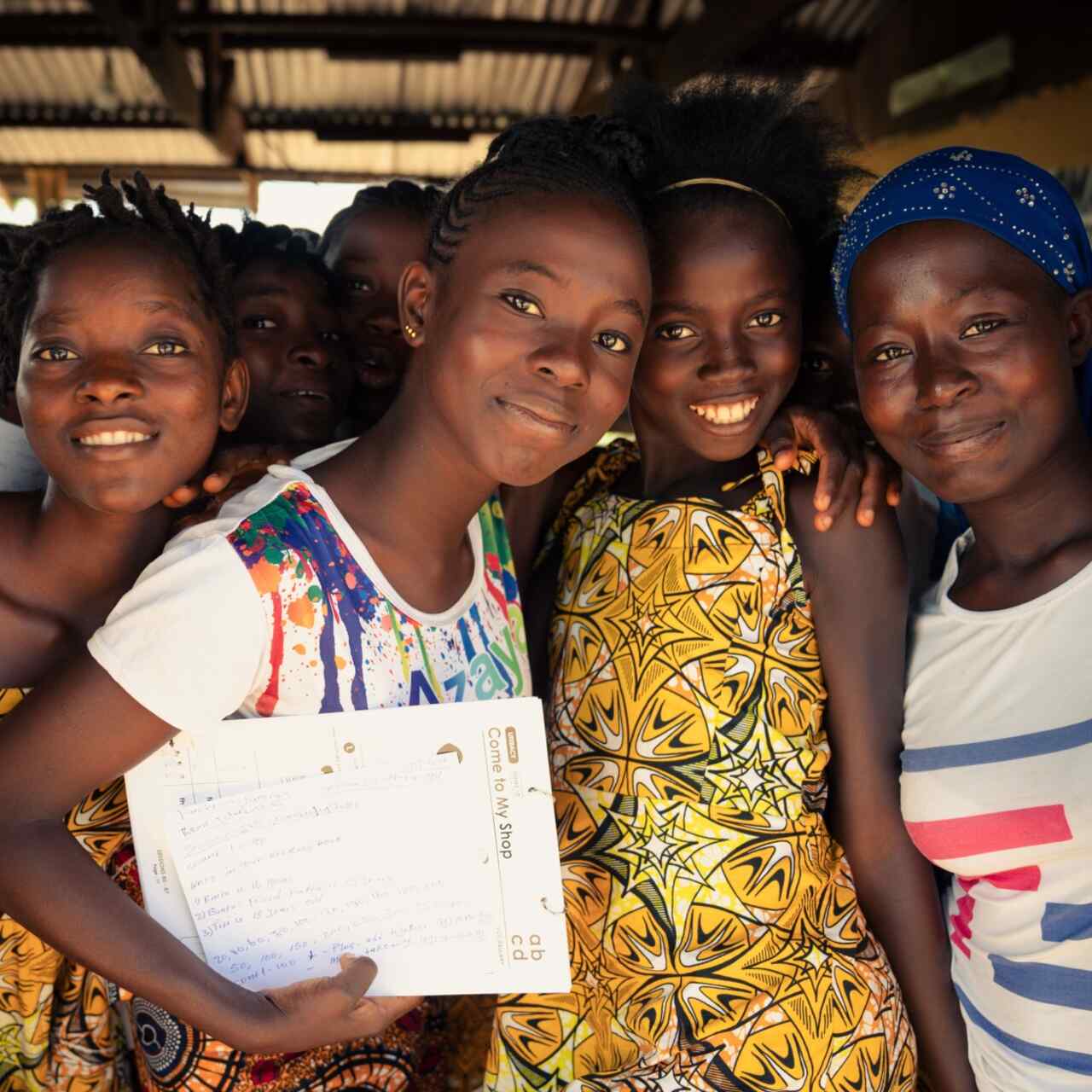 Adolescent girls attend an EAGER session in Tongo Community, Sierra Leone. A group of them pose for a photo together.