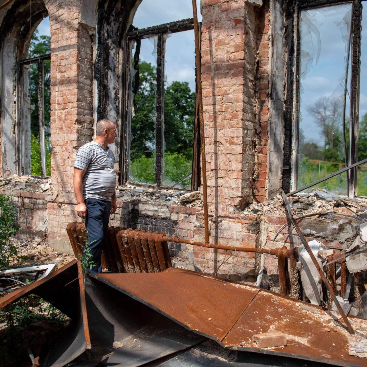 A middle-aged man walks through the ruins of a destroyed building.