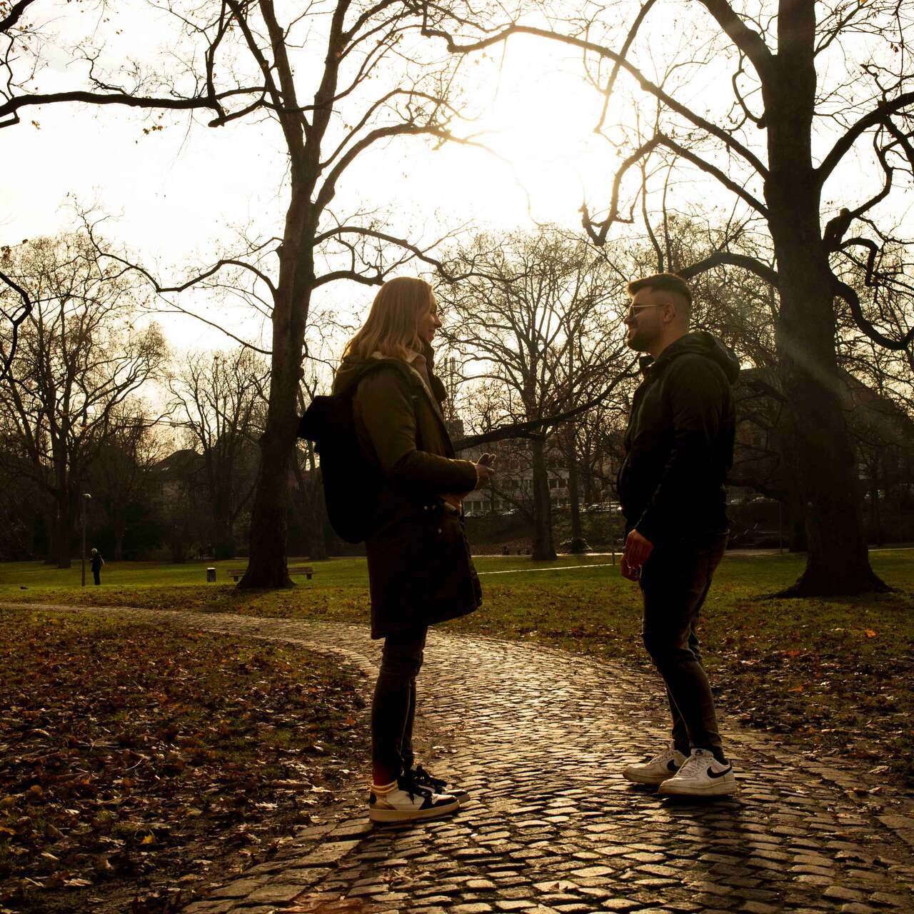 Ein junger Mann und eine Frau stehen draußen in einem Park.