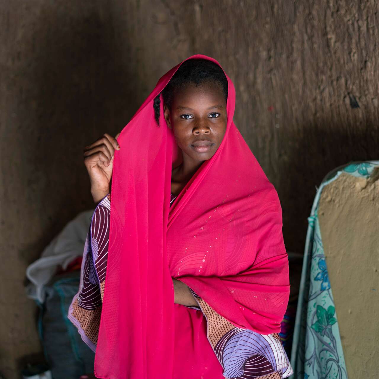 A schoolchildren in Niger, wearing a pink outfit, poses solemnly for a potrait