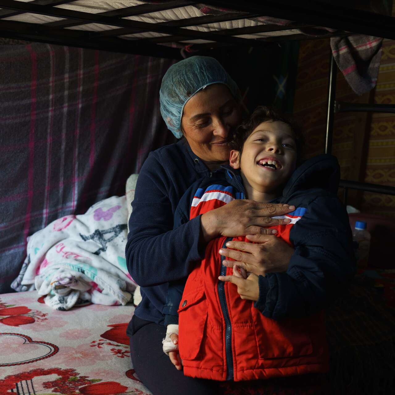 Sara*, 36, from southern Mexico, is pictured with her nine-year-old son in her bunk at Oasis del Migrante shelter in Ciudad Juárez. Sara has been waiting for an appointment via the CBP One application to seek entry into the United States with her sons, hoping to get better medical care for her nine-year-old son’s cerebral palsy. 