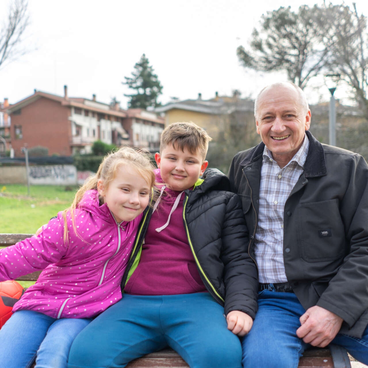 Oleksandr sits on a bench with his two grandchildren.