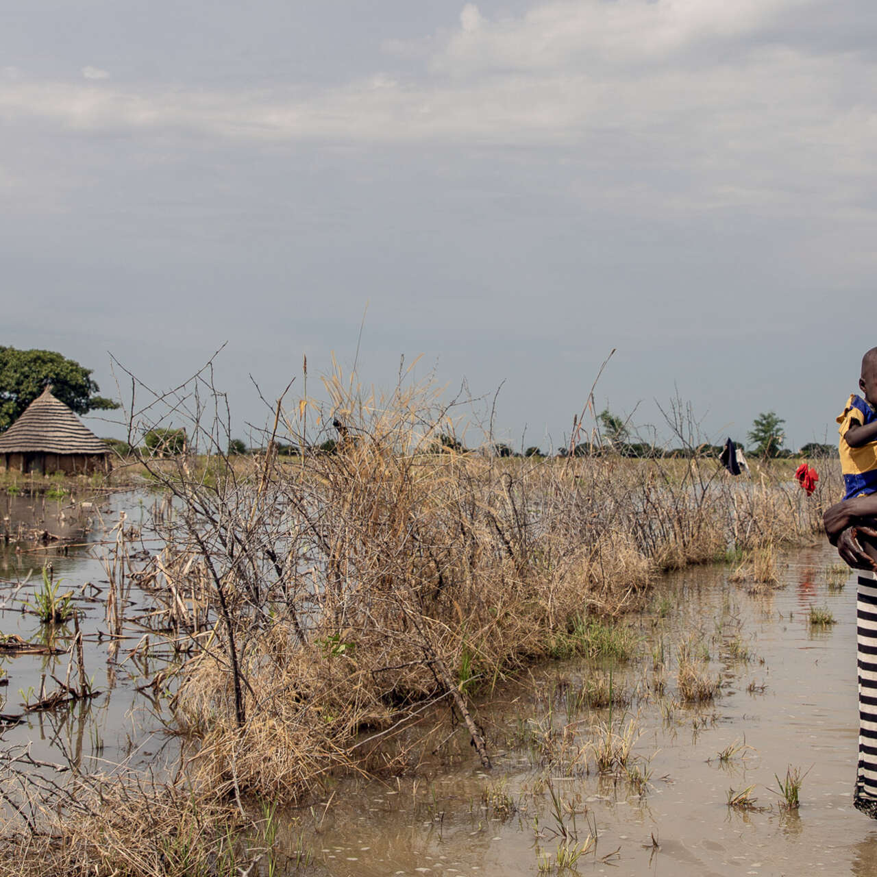 Eine Mutter hält ihre Tochter fest an der Brust, während sie in einer überschwemmten Region von Südsudan spazieren geht.