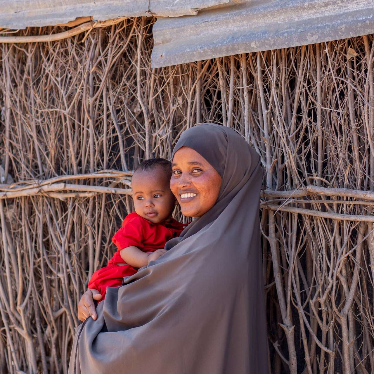 A mother holds her young child in her arms and the pair poses for a photo.