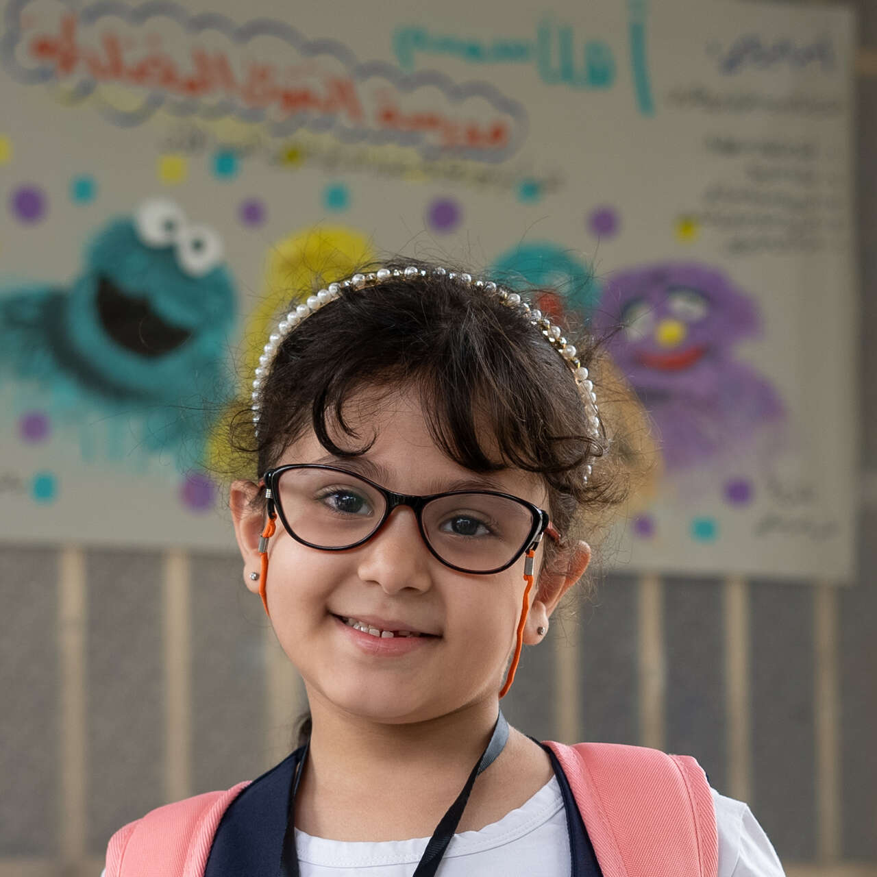 A girl in glasses poses for a photo in an IRC classroom in Iraq.