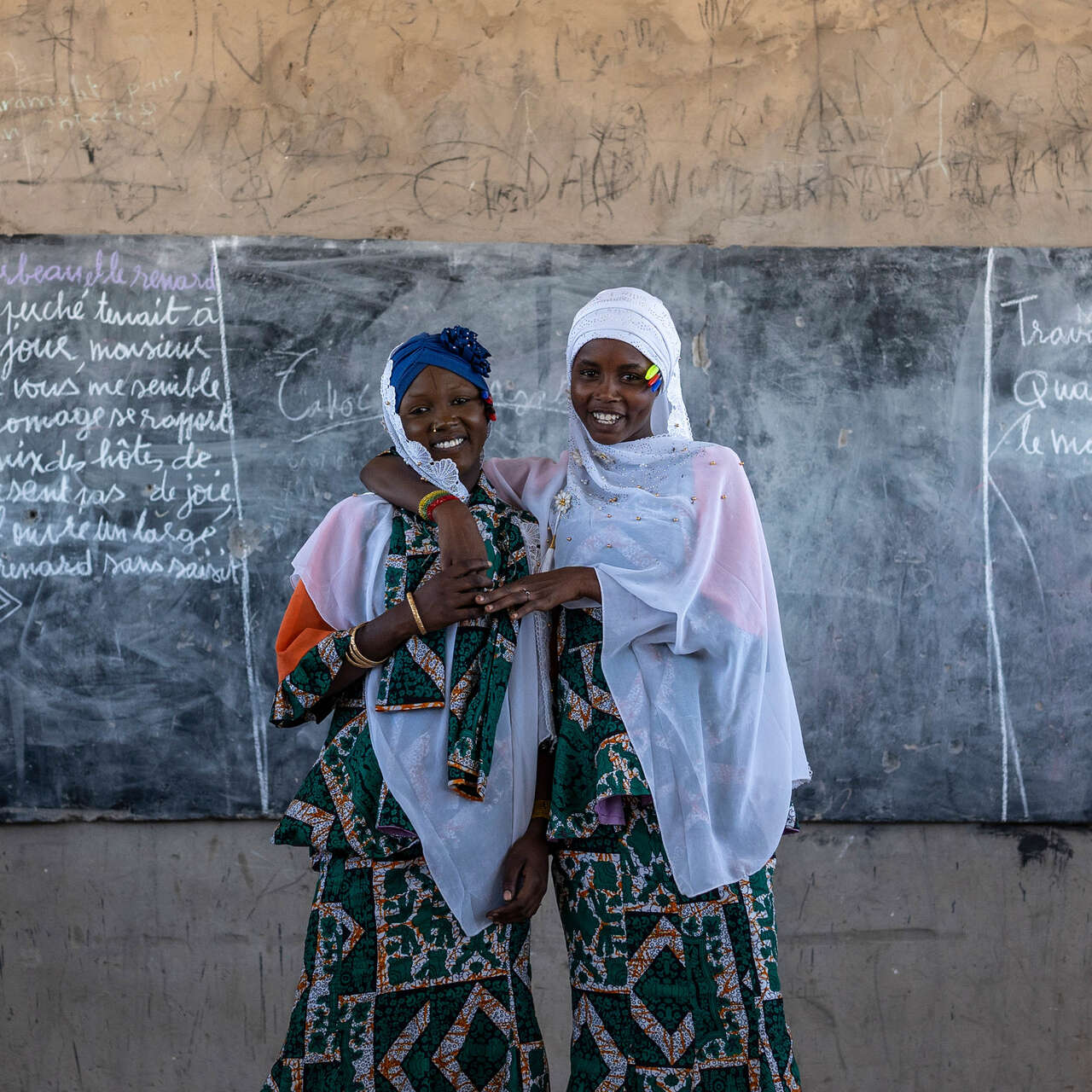 Two women stand together at the front of a classroom in Chad.