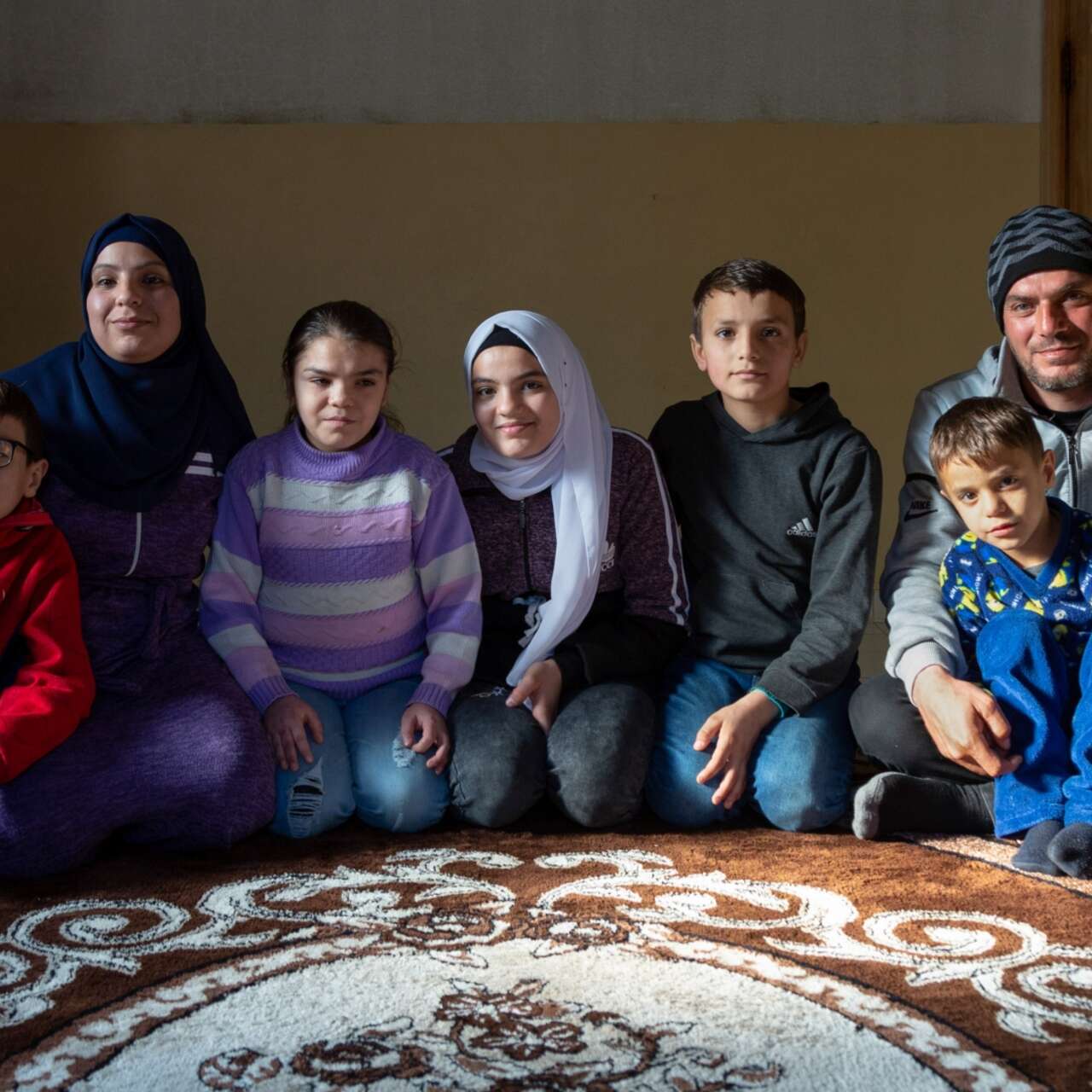 A family of Syrian refugees sit together in their home in Lebanon.