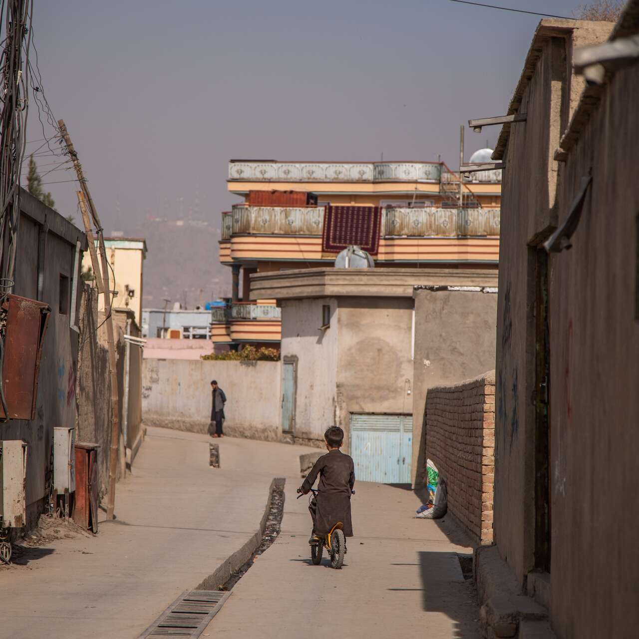 Ein Junge fährt mit dem Fahrrad durch eine Gasse in Afghanistan