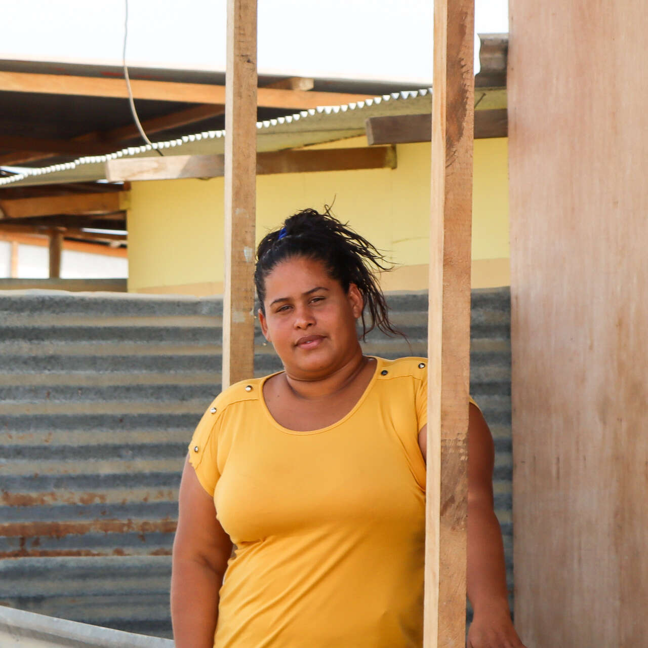 A woman stands outside her home in Peru and poses for a photo.