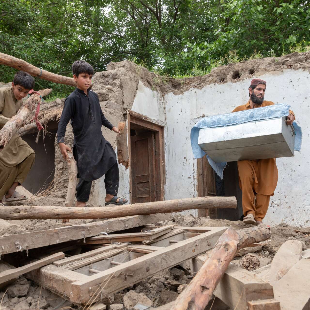 A family carries furniture out of the ruins of their home in rural Afghanistan after it was destroyed by flooding.