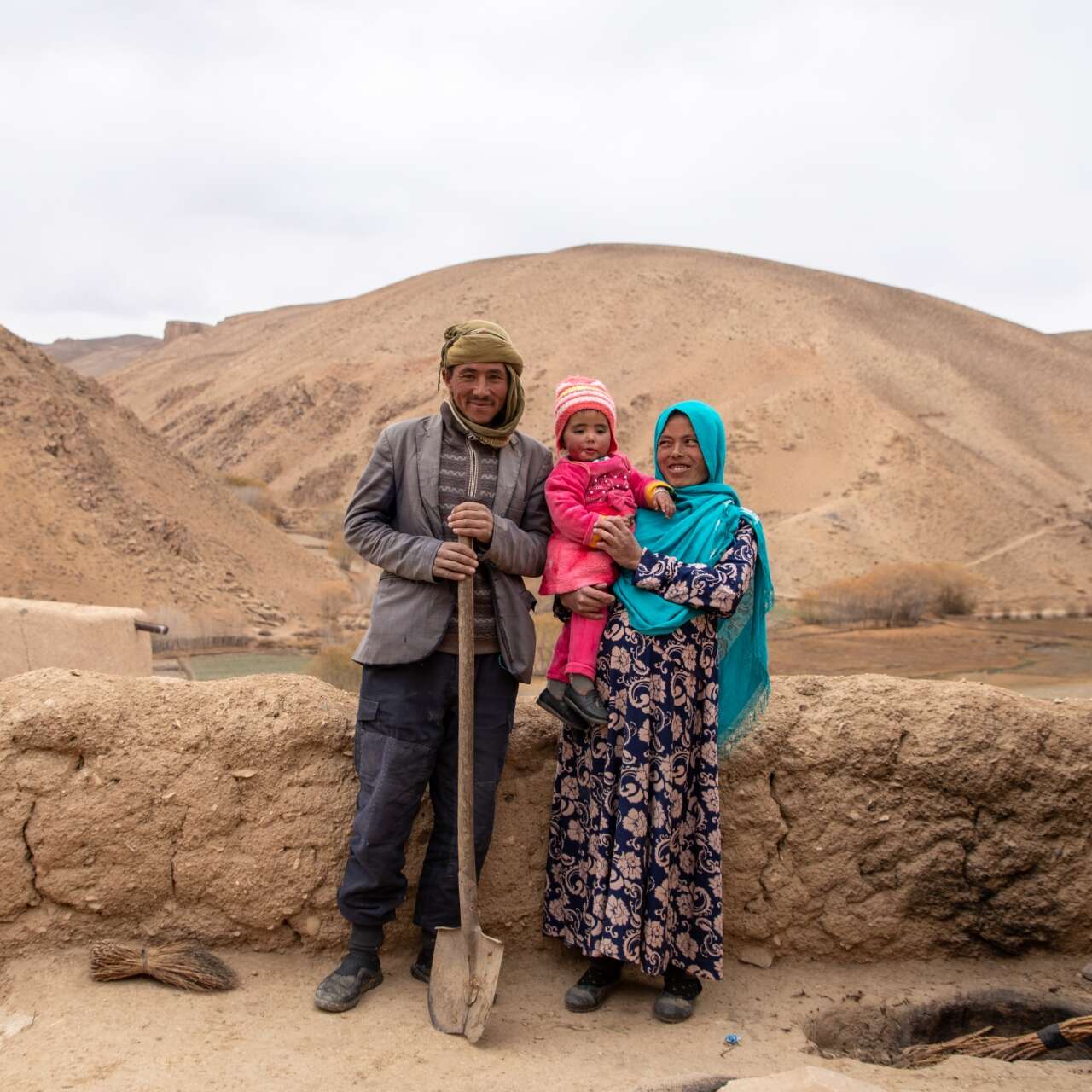 A family of three poses for a portrait in rural Afghanistan.