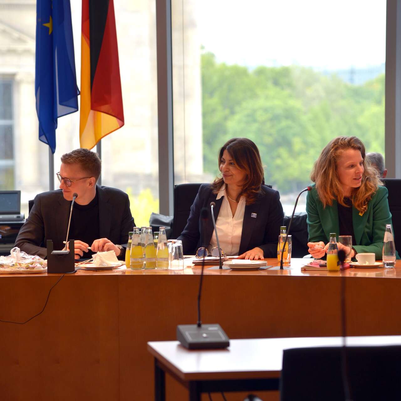  Eine Gruppe von Personen sitzt an einem Konferenztisch, im Hintergrund sind die Flaggen der Europäischen Union und Deutschlands zu sehen