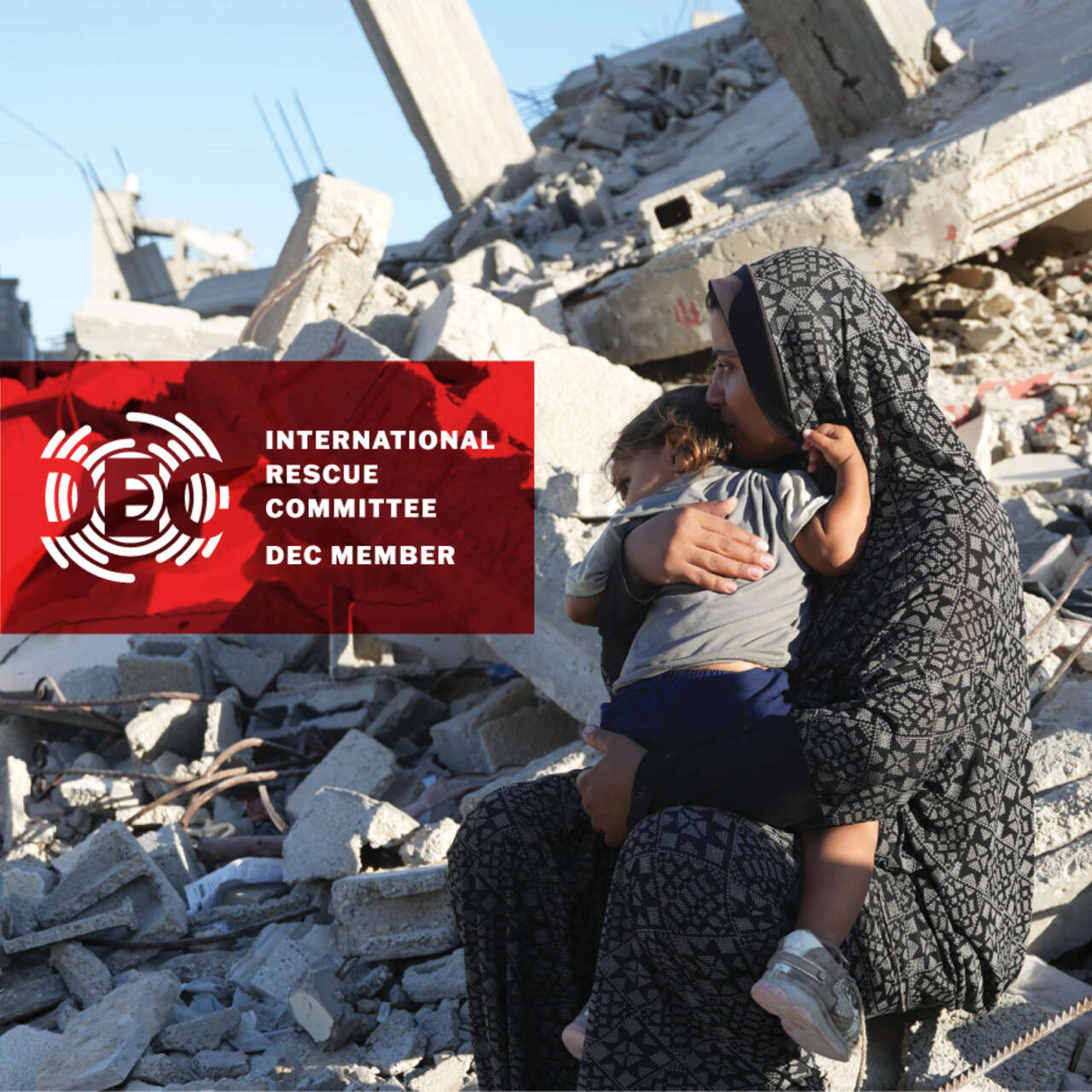 Woman holding a child amongst rubble in Gaza