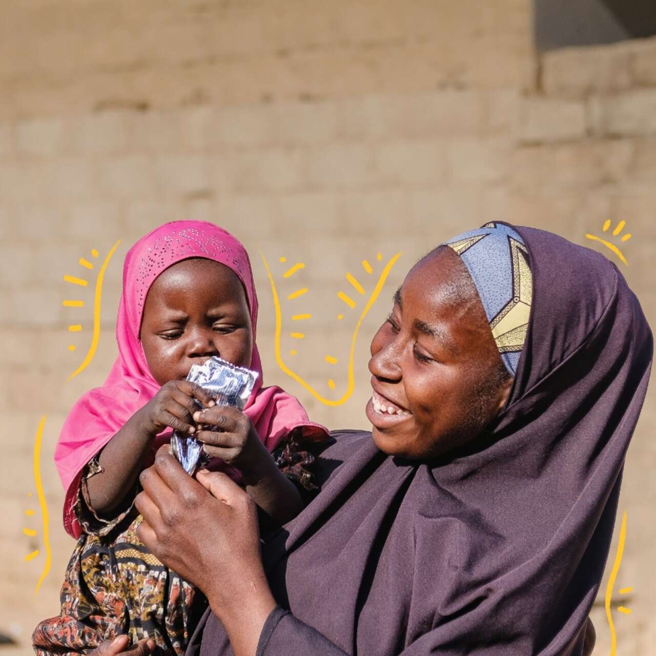 A mother holds her daughter in her arms as she eats a nutritious treatment for malnutrition.