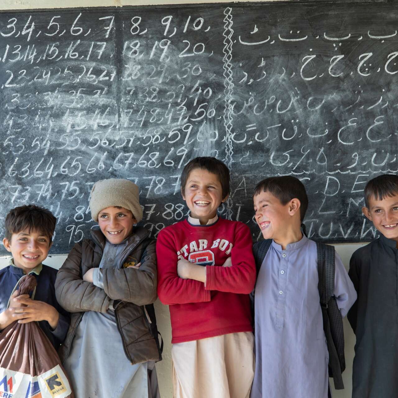 A group of boys smile and pose for a photo at their school in Paksistan.