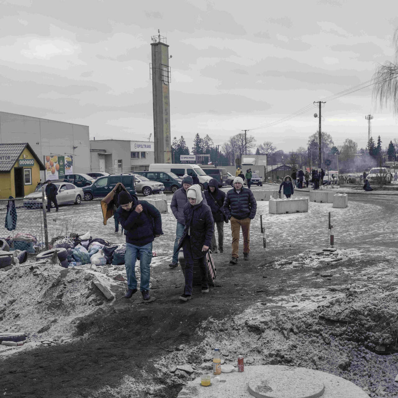 Refugees arrive at Medyka border crossing point, Poland. They are wearing warm clothing, around them, snow lies on the ground. 