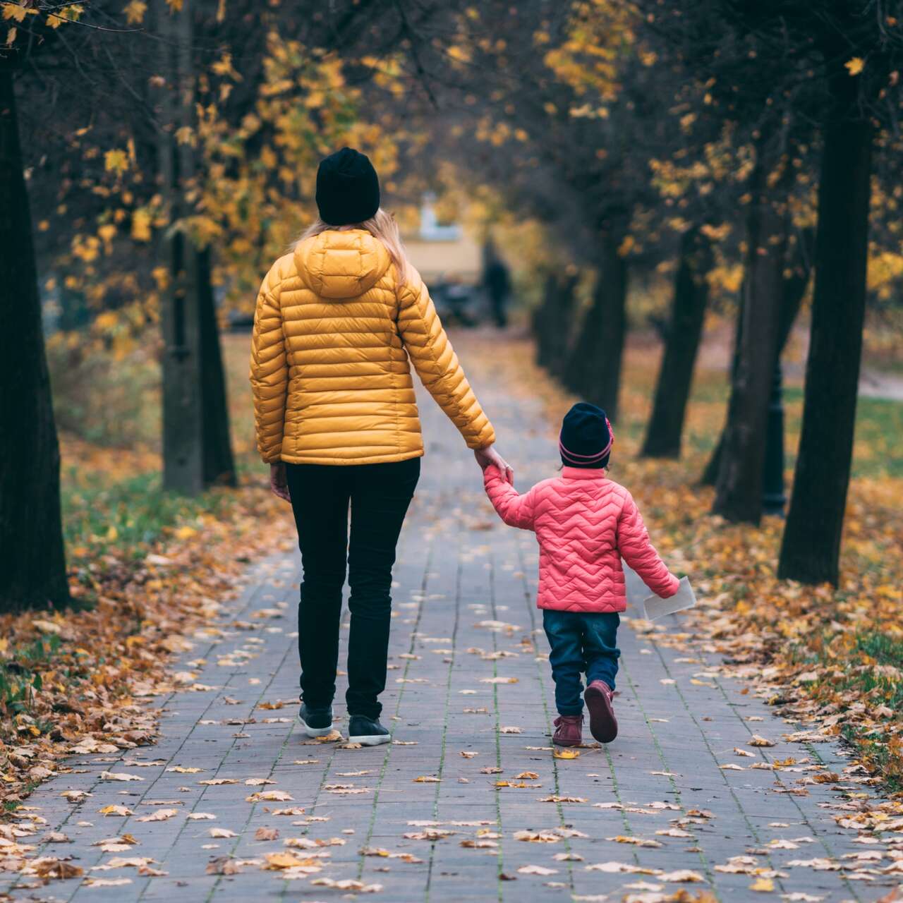 Frau und Kind Hand in Hand in einer Allee