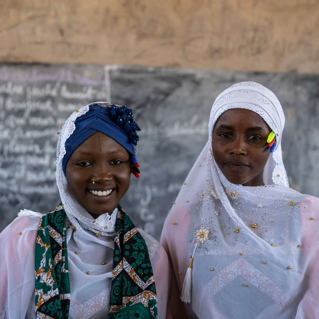 Two students stand at the front of a school in Chad and pose for a photo.