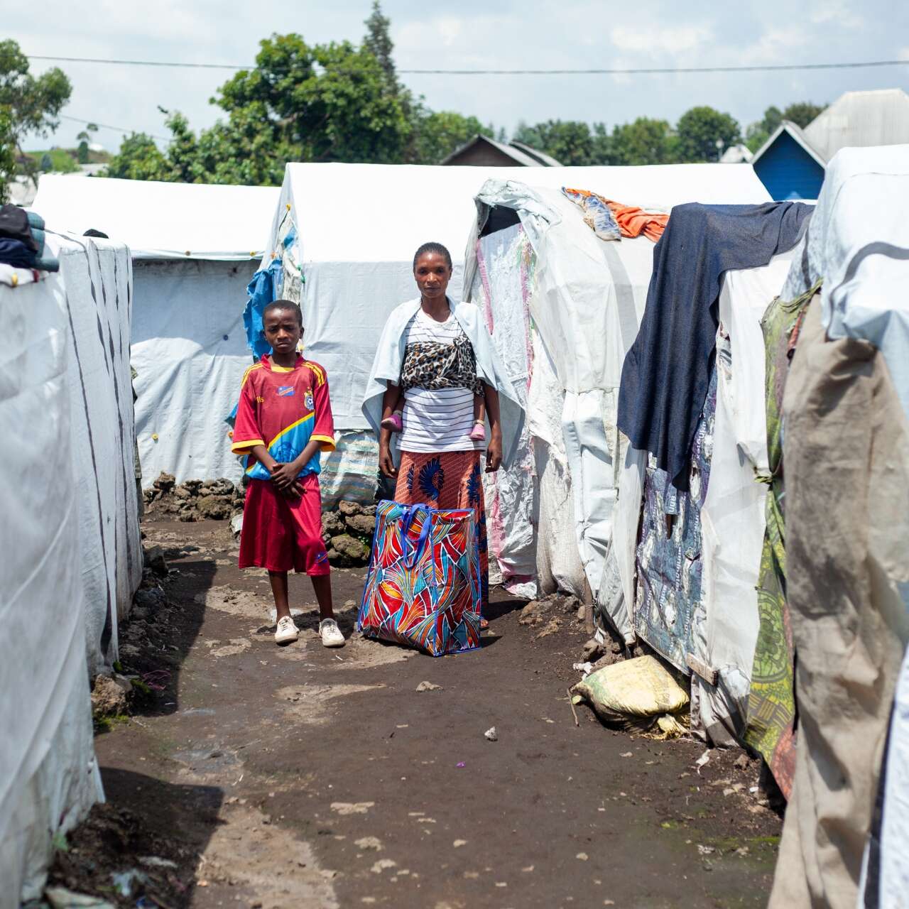 A son stands next to his mother at a camp for displaced people in the DRC.