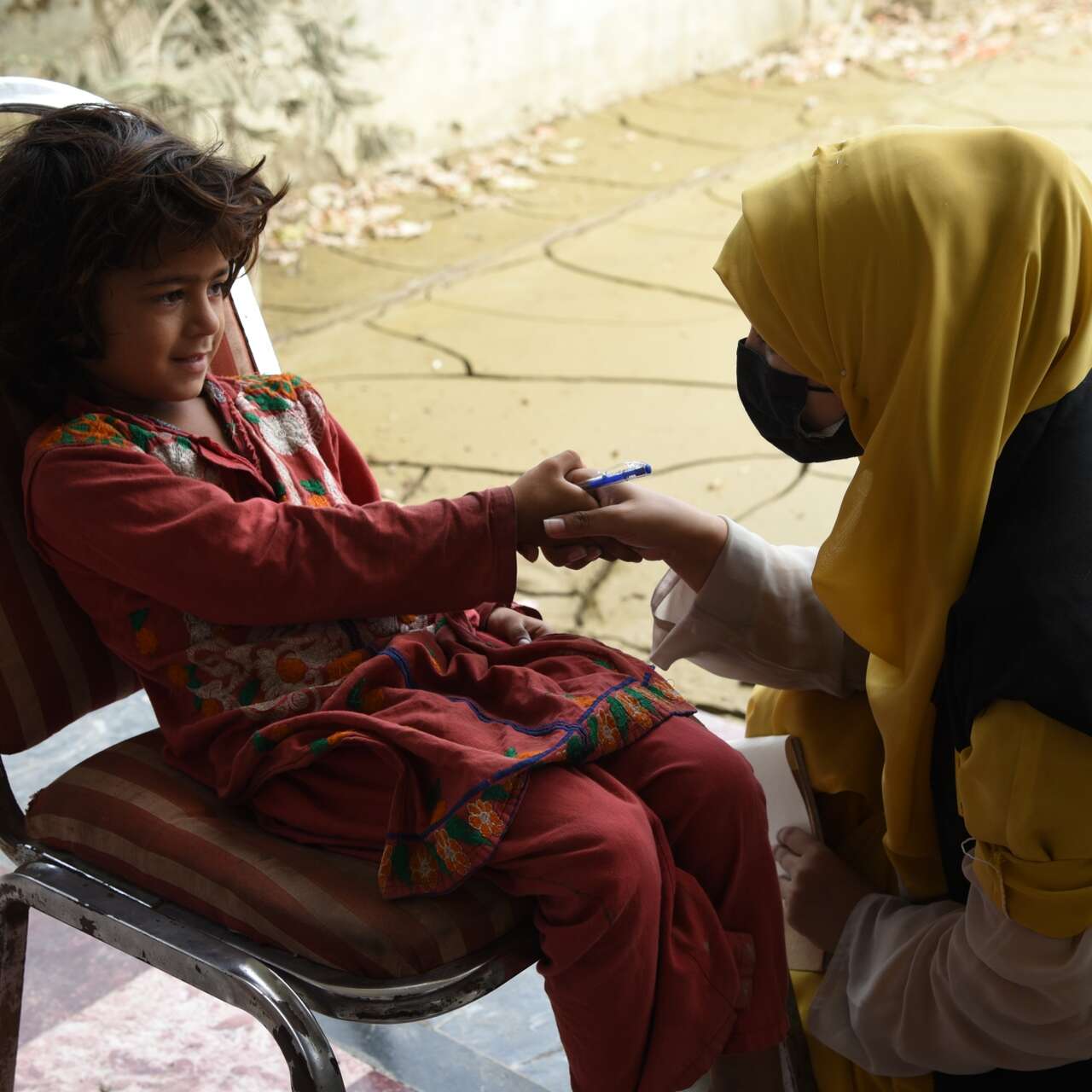 An IRC staff member greets a young girl at an IRC health clinic in Pakistan.