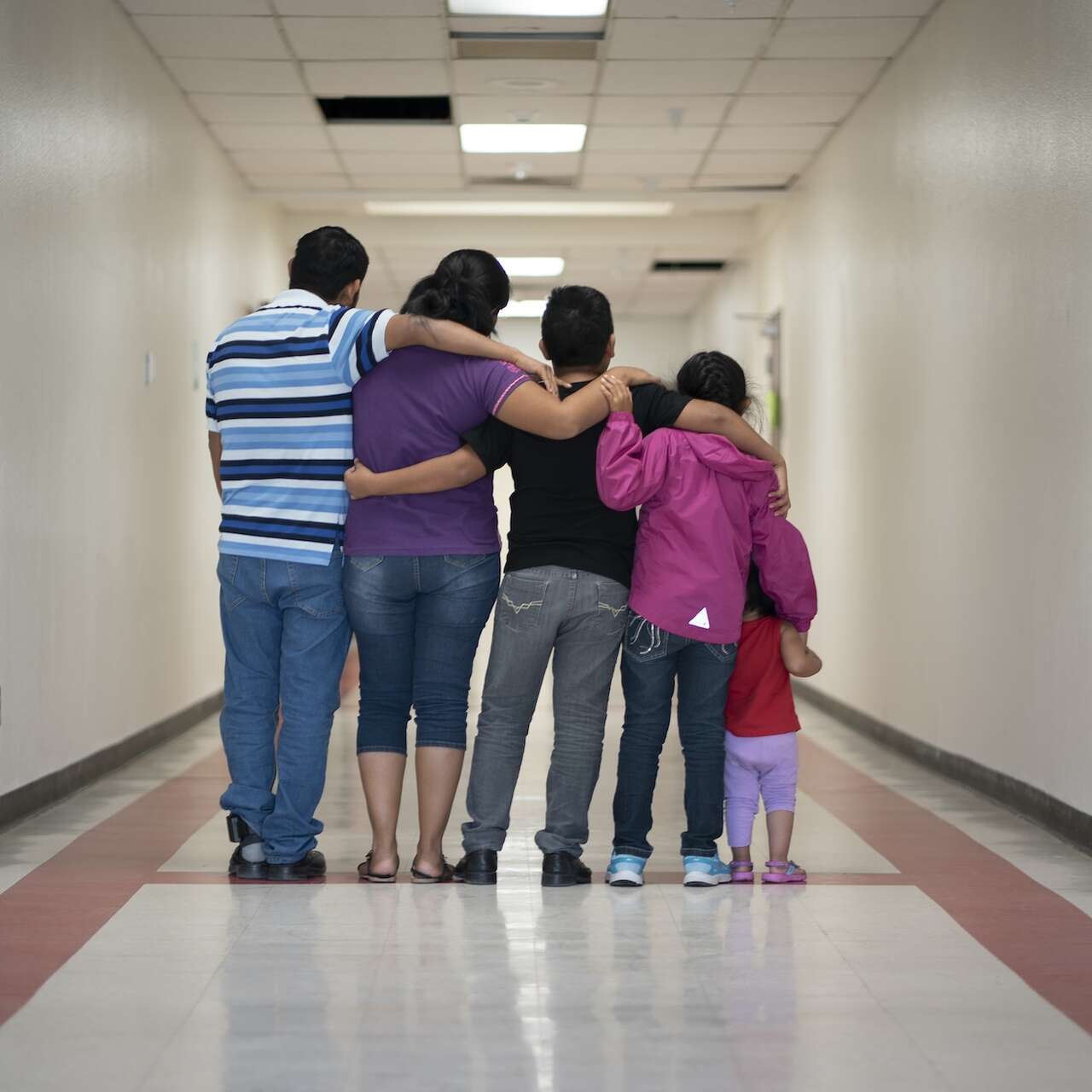 A family of 4 have their backs turned and arms around each other