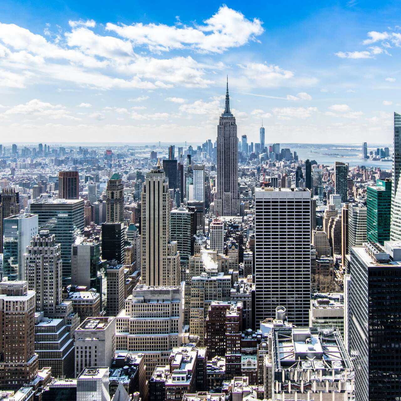 Aerial view of New York City skyline with skyscrapers under a blue sky.