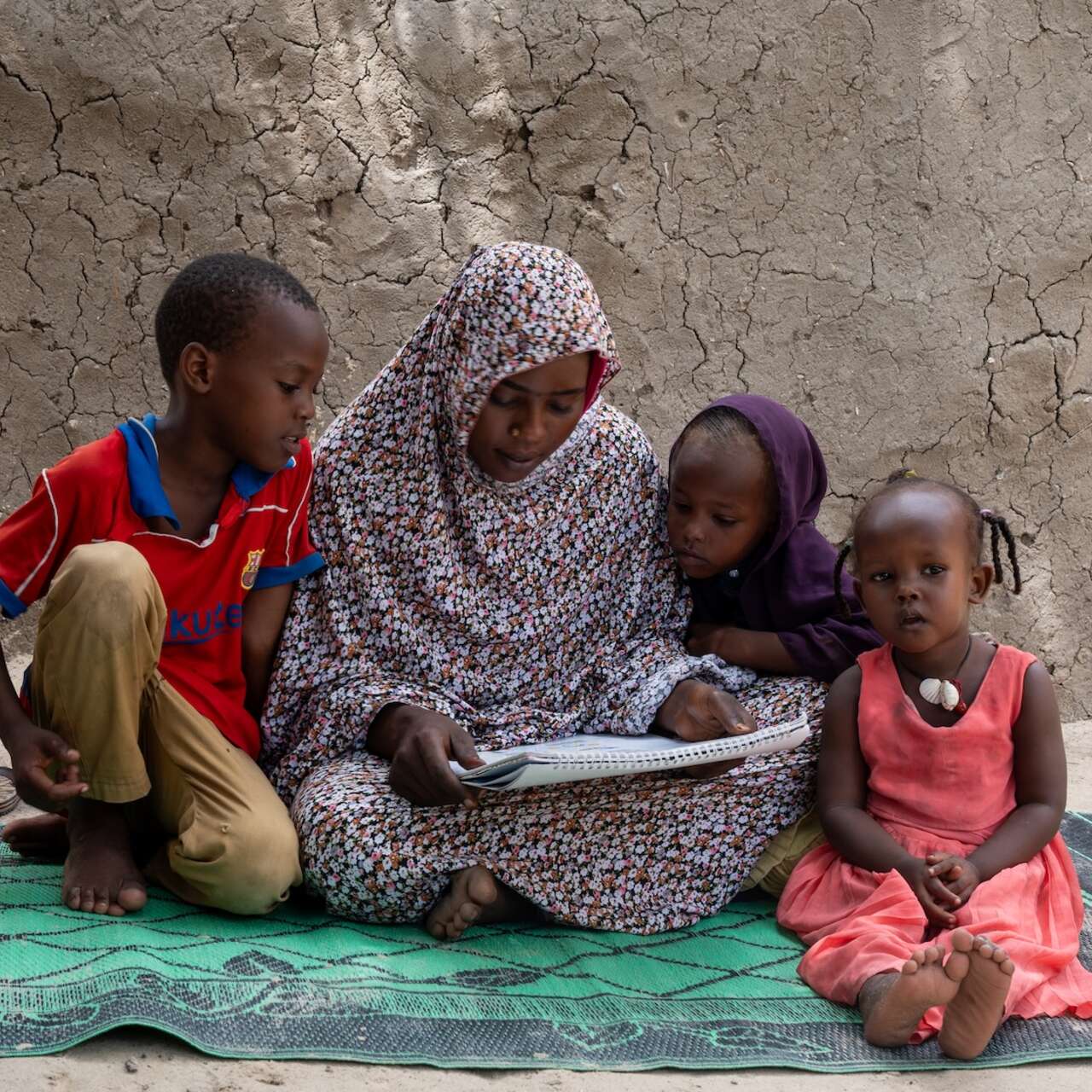 A woman reading surrounded by 3 young children