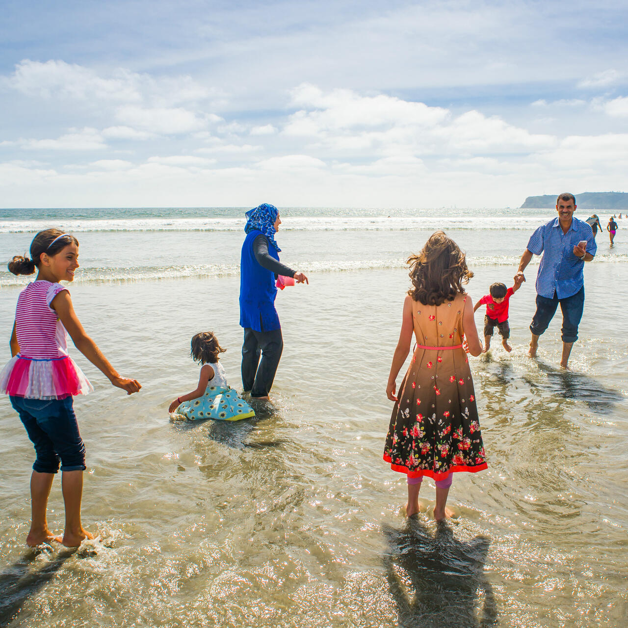 The Tlas family, Syrian refugees, plays in the surf at a California beach.