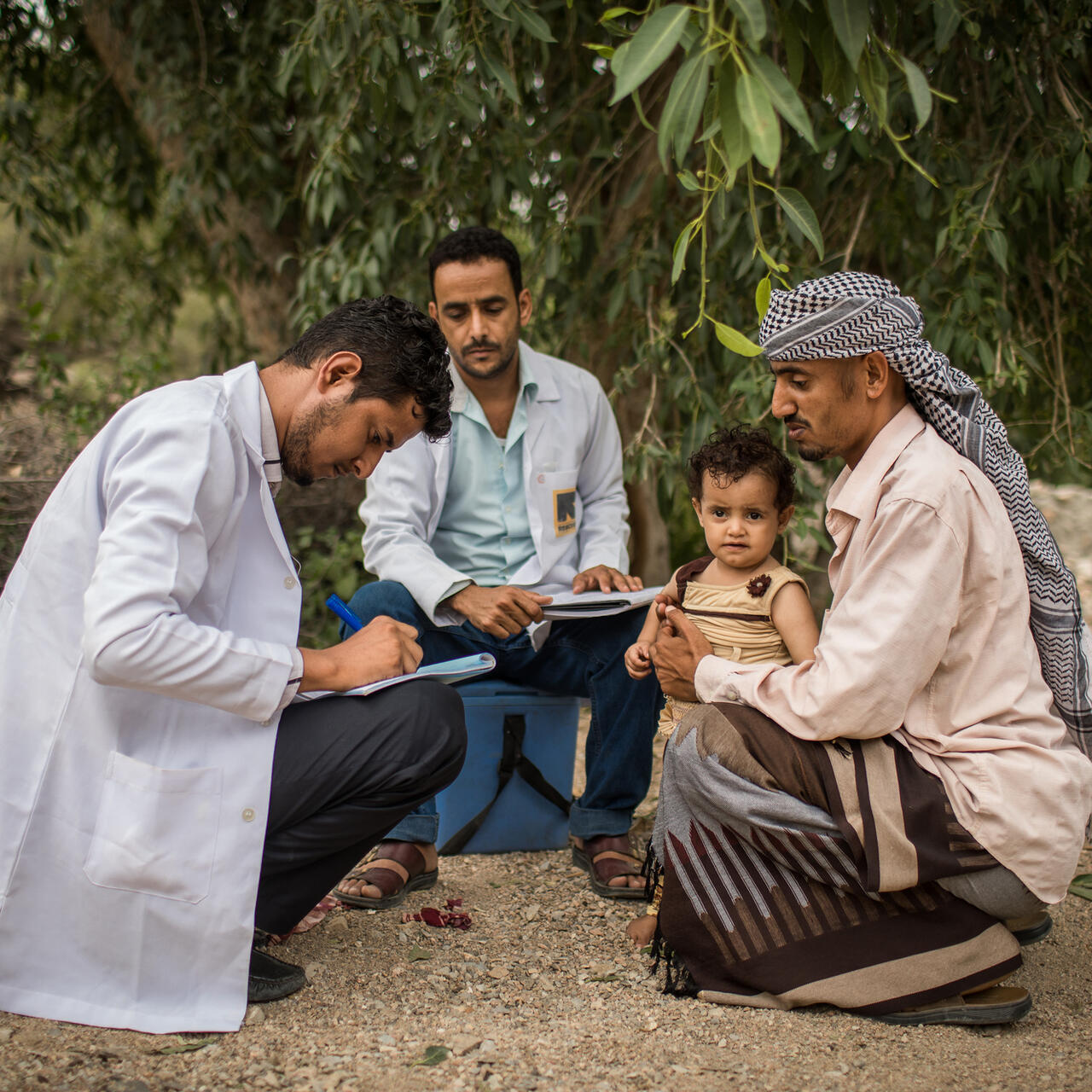 IRC health workers examine a child being held by his father in the village of Mosuk, Yemen
